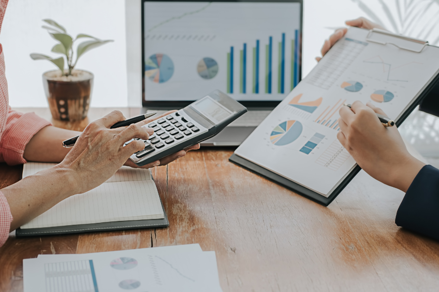 How Much Does E-Invoicing Actually Cost a Mid-Size UAE Business? A Real Breakdown 3 Financial professionals reviewing business performance charts and calculating costs during a financial analysis meeting