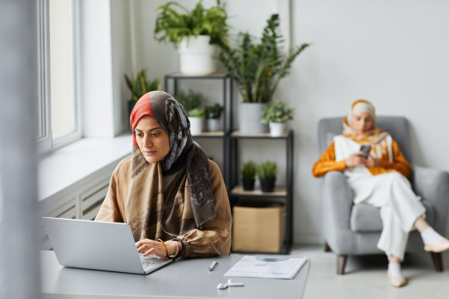 Are You Spending Too Much on SAP DRC for UAE E-Invoicing? 2 Muslim woman working on a laptop at home while another woman relaxes in the background